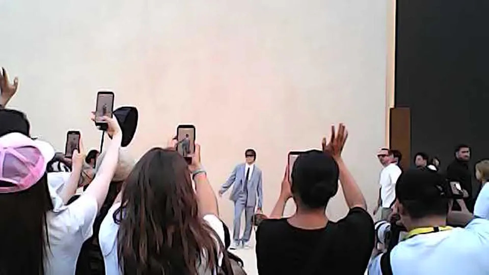 People use their smartphones to photograph a person in a suit and tie