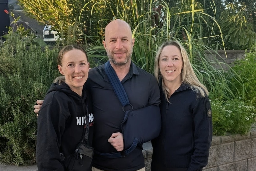 A man in a sling in between two women