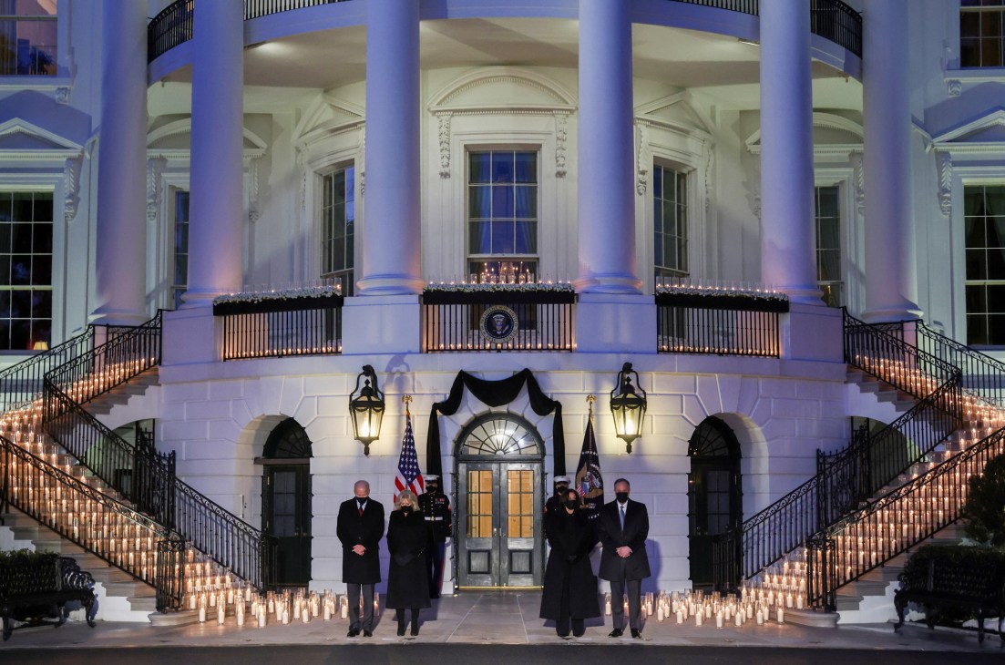Biden and others holding candles at a memorial vigil on the White House lawn