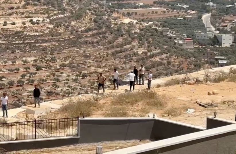 Israeli settlers gather outside a Palestinian home in Qusra, in the West Bank, August 15, 2026, in this screen grab obtained from a video.