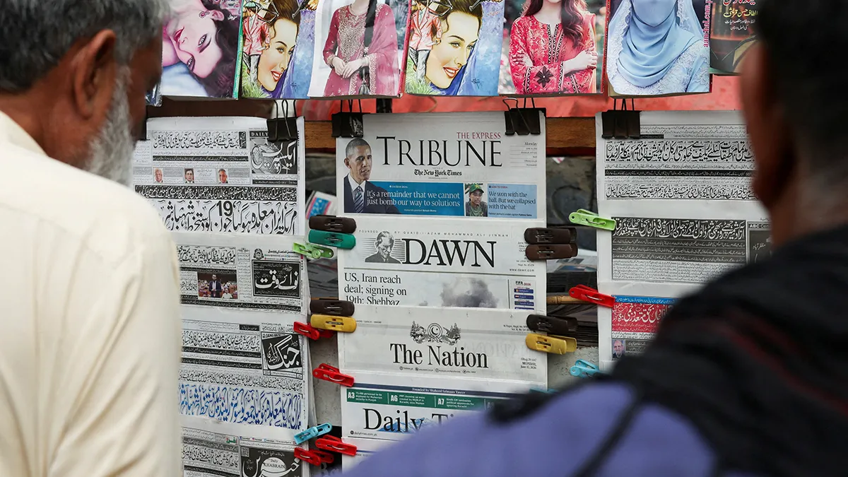 Men read newspapers reporting on the signing of the US-Iran peace agreement at a newsstand in Islamabad, Pakistan, on 15 June 2026 - REUTERS/ AKHTAR SOOMRO