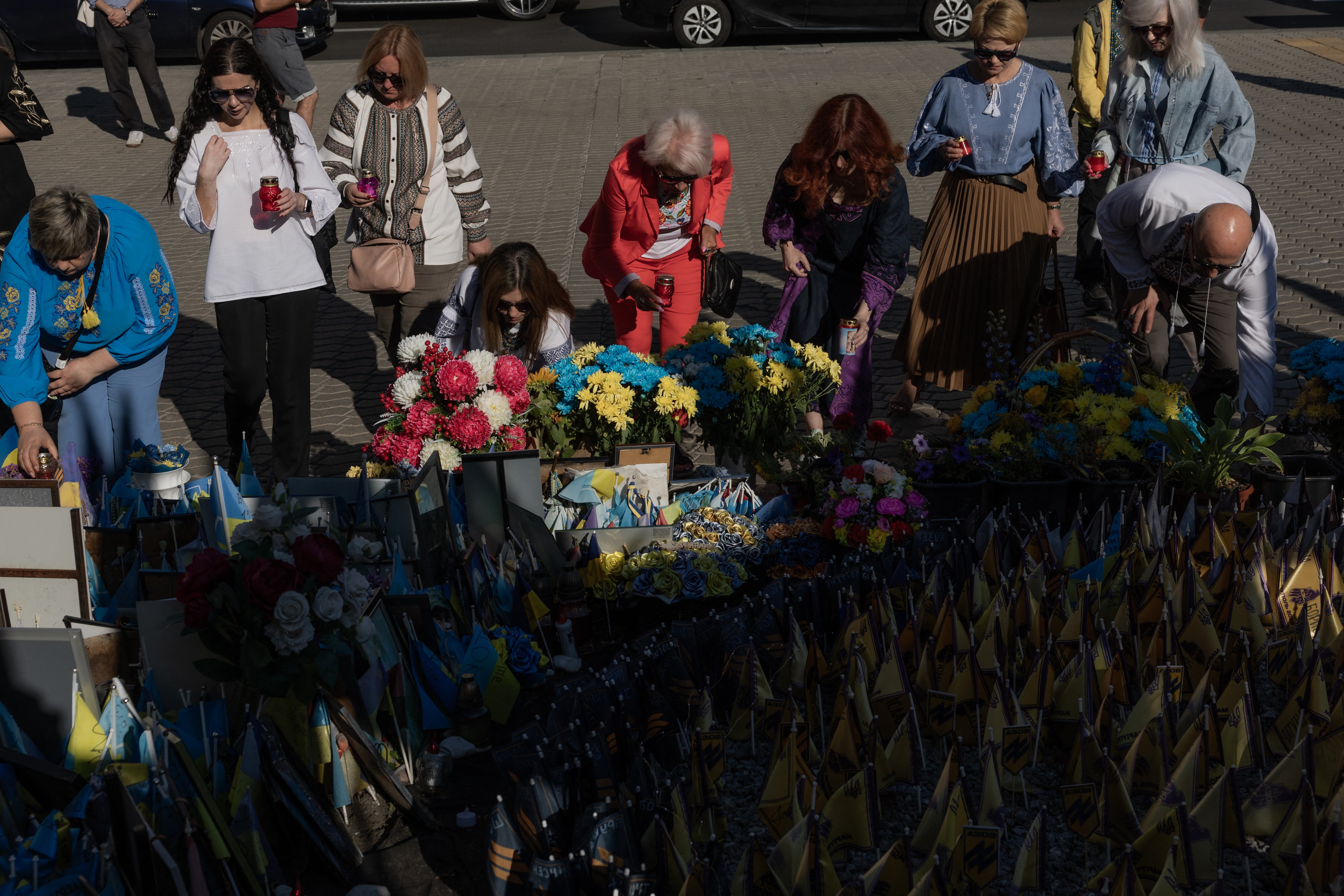 People lay lamps as a tribute during a visit to a makeshift memorial for fallen Ukrainian and foreign soldiers on Independence Square in Kyiv on Ukraine's Independence Day, on August 24, 2026