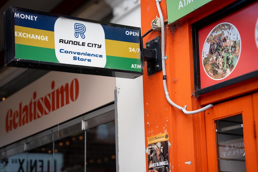 A bright orange store front with a sign above it reading 'Rundle City Convenience'