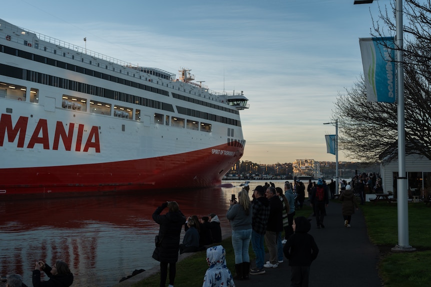 Crowds gathered along river at Sunrise, watching loom over them as it cruises down river