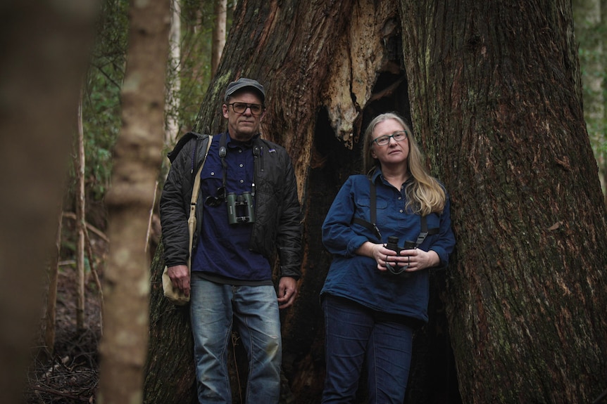 Matt Webb (left) and Leanne Wicker stand side-by-side beside tall trees.