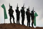Hamas militants are seen standing between two green flags while wearing all black and holding guns.