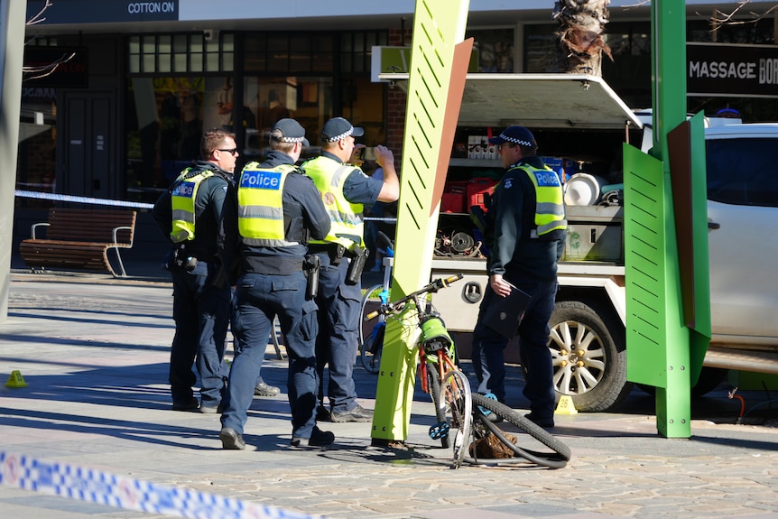 A mangled bike, near a white work ute in a pedestrian mall