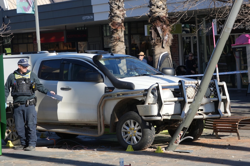 A white Ford ute which has collided with a light pole