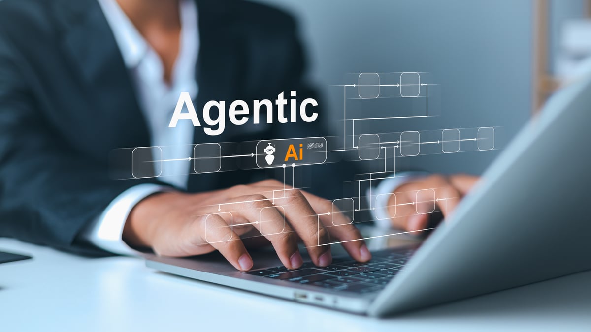 An investor types into a laptop with the words "Agentic AI" floating above.