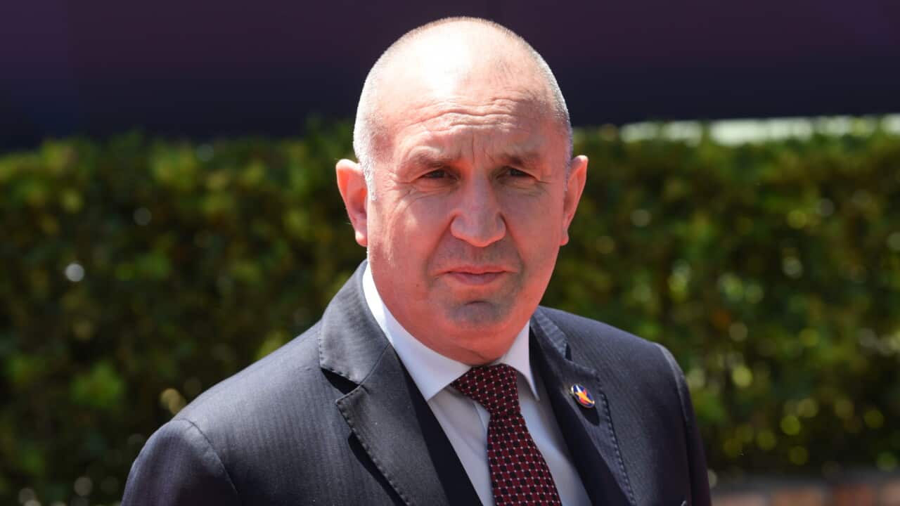 A balding older man in a dark suit and red tie.