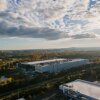 This photo taken from high above shows a Meta data center in Ashburn, Virginia, in 2025. It is a large, long light-colored building with few windows, and it's nestled among trees and a few other buildings with a similar shape.