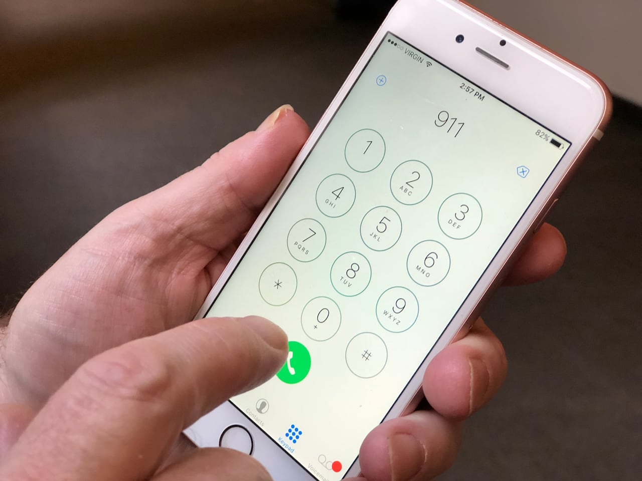 A closeup shows a hand holding a cellphone with the numbers "911" on the screen.