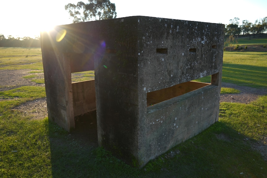 A concrete shelter for a world war two gun on a sunny, grassy field