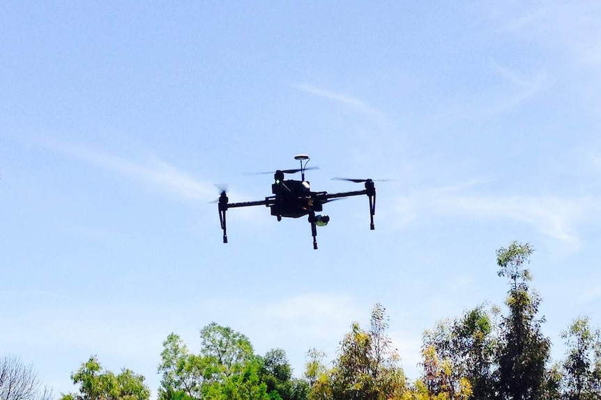 a black drone hovers in the air
