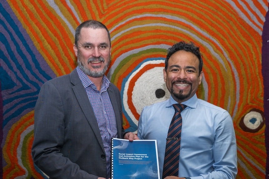 Two men holding a report. 