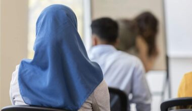 Rear view of woman wearing hijab sitting in classroom.