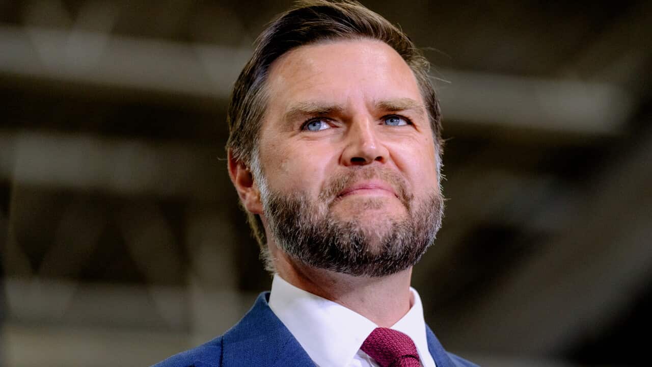 JD Vance, wearing a blue blazer, white shirt and red tie.