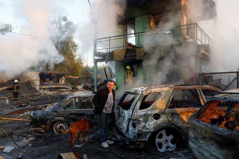 A resident with a dog looks on at the site of private car garages hit by a Russian missile strike in Kyiv, Ukraine on October 7, 2026 [Valentyn Ogirenko/Reuters]